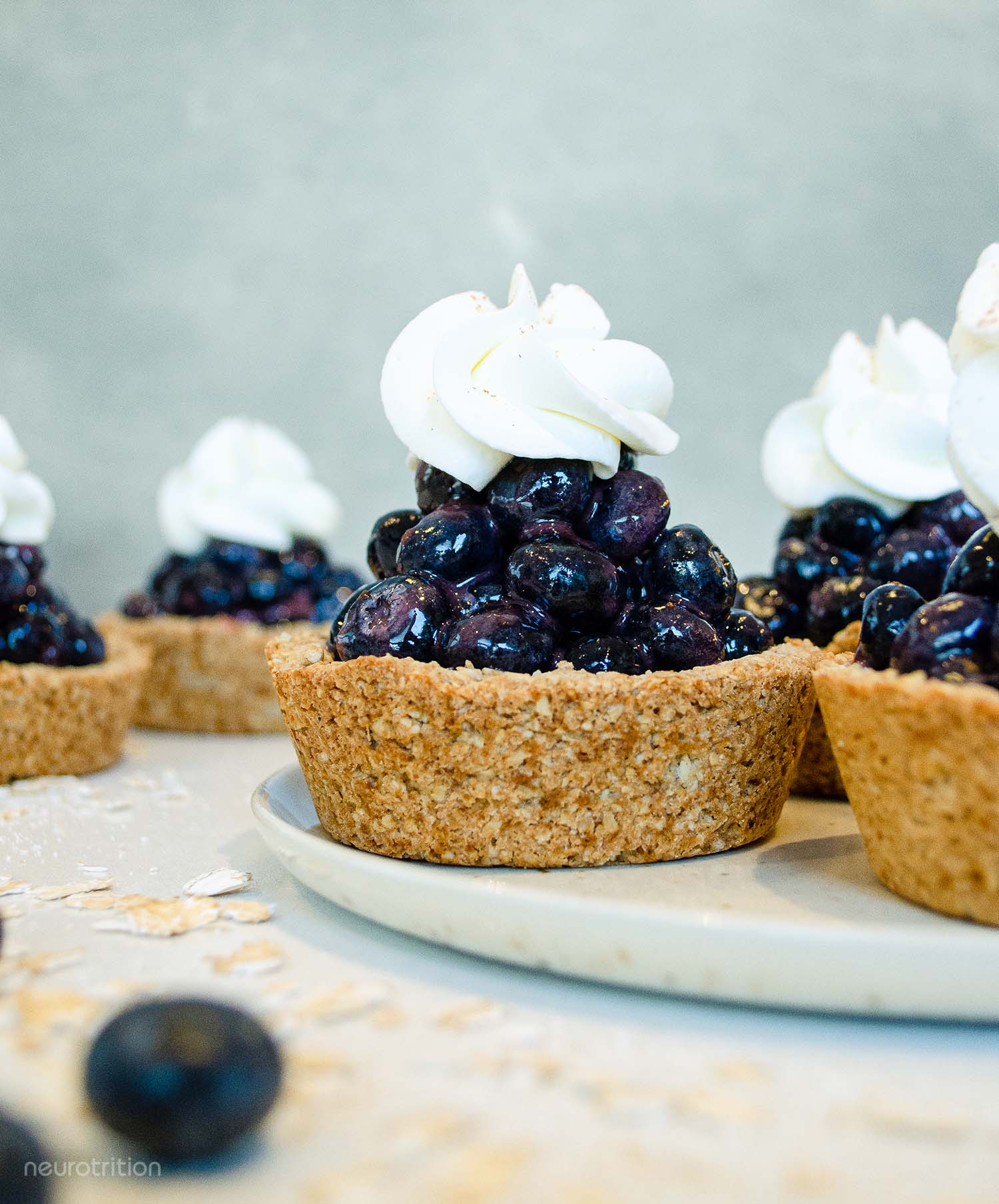 A group of mini blueberry pies with a dollop of whip cream on top of each.