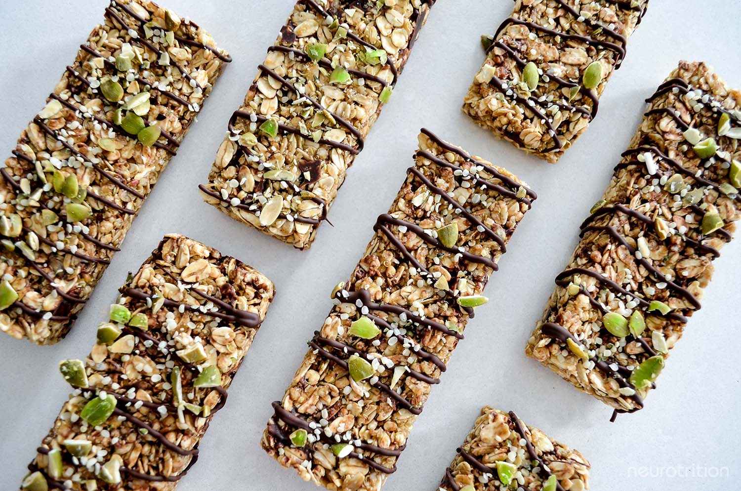 Flatlay of several granola bars in a grid formation, with chocolate drizzled across all the bars.