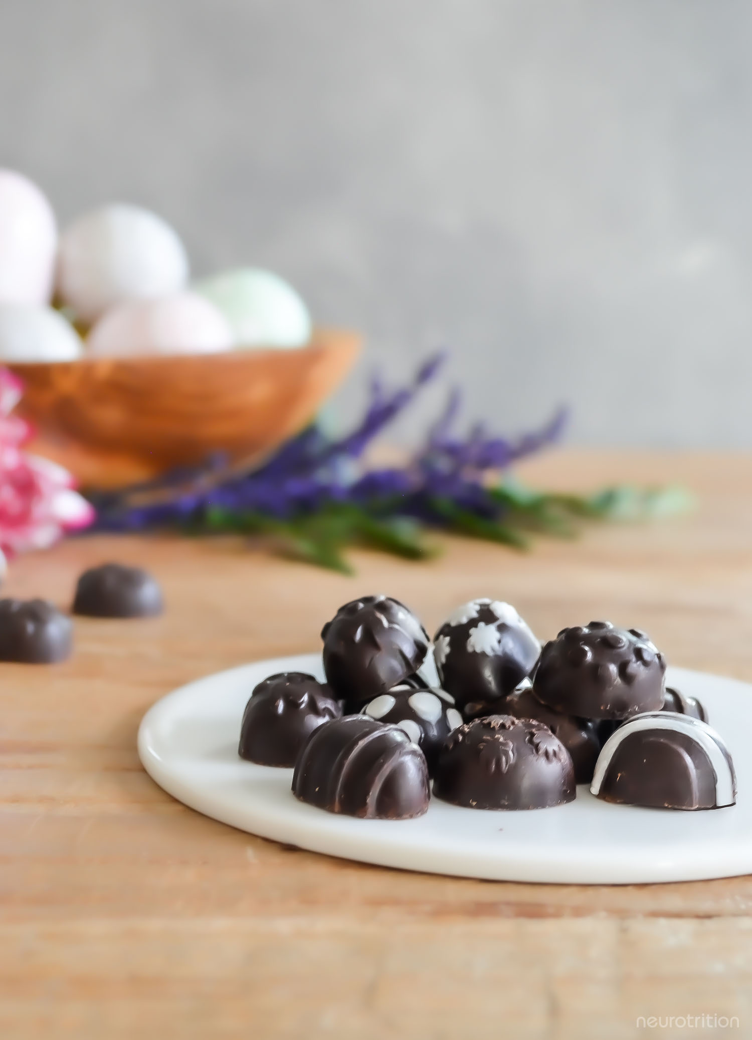A pile of homemade chocolate Easter eggs with decorative white icing, on a white plate.