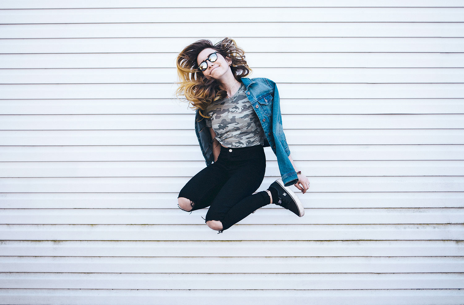 Woman jumping in front of wall.