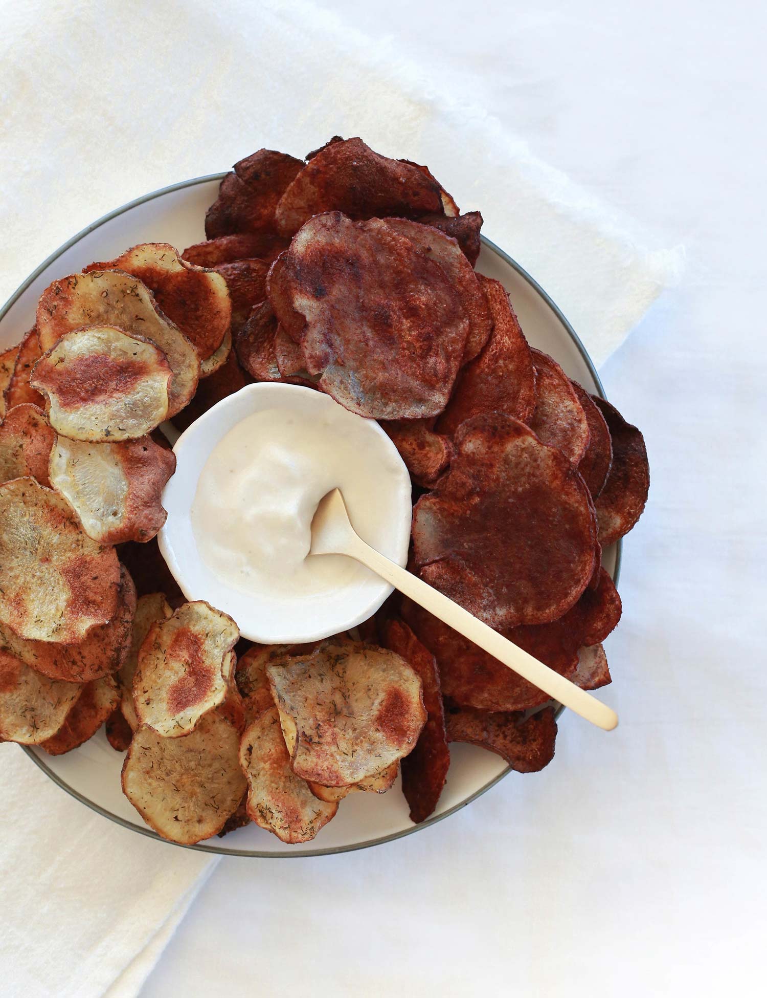 2 flavours of potato chips on a plate with dip in the middle