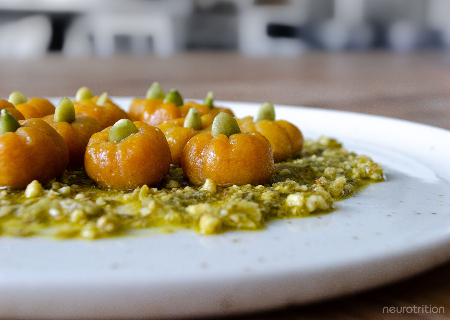 Plate of pumpkin-shaped orage pasta on a bed of pesto.