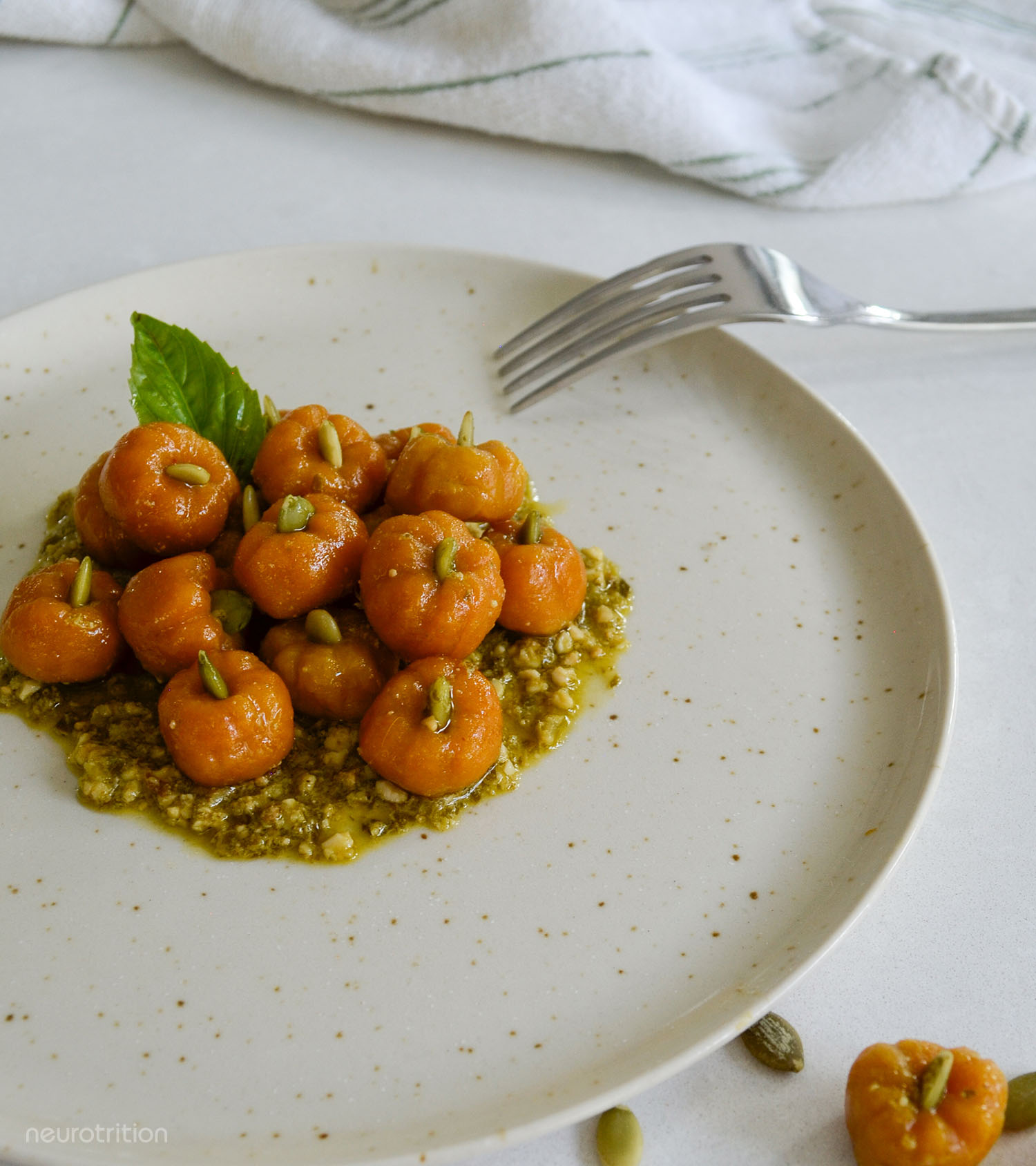 Plate of pumpkin-shaped orage pasta on a bed of pesto.