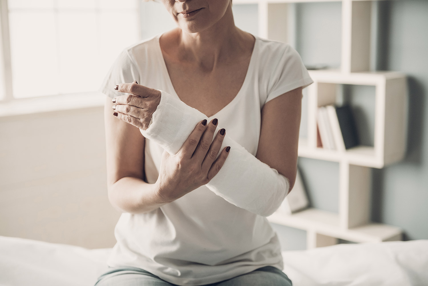 Woman holding her broken arm with cast