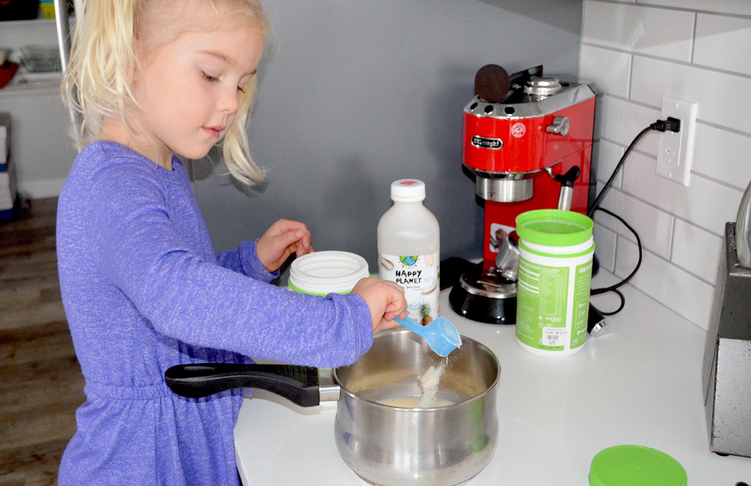 Little girl putting gelatin into a pot