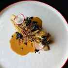 Charred cabbage with almond coconut yogurt sauce & seaweed furikake on a white plate with red trim